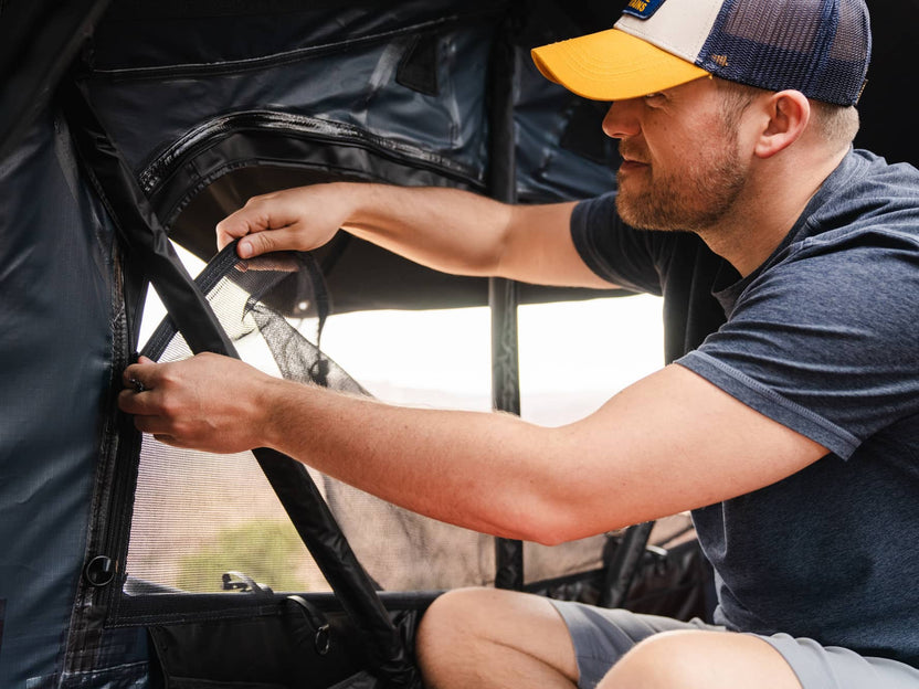 Man zipping up the bug mesh panel inside the TentBox Lite XL rooftop tent