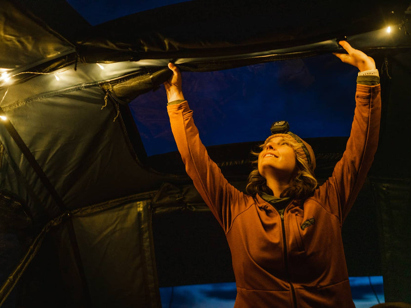 Rolling down the skylights window panels ready for a good night sleep inside the TentBox Lite XL rooftop tent, which is lit up using the string lights included.