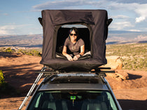 Woman enjoying the Utah desert views from inside the TentBox GO, installed on top of her car