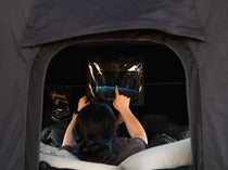 Woman watching a film through the iPad sleeve included with the TentBox GO