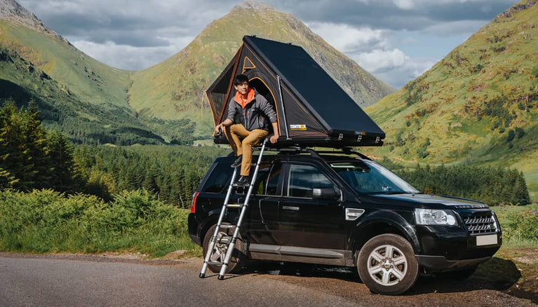 A TentBox cargo roof tent on a Land Rover Freelander with a camper sat inside