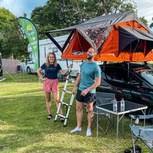 Two people at a camp site with their TentBox Lite roof tent installed on their car