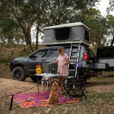 A woman in Australia cooking at a campsite with her TentBox Classic 1.0 in the background