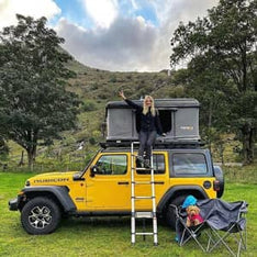 A yellow Jeep Rubicon with a TentBox Classic tent attached to the roof rack