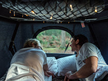 Two people lying inside a TentBox Classic roof tent, enjoying the view