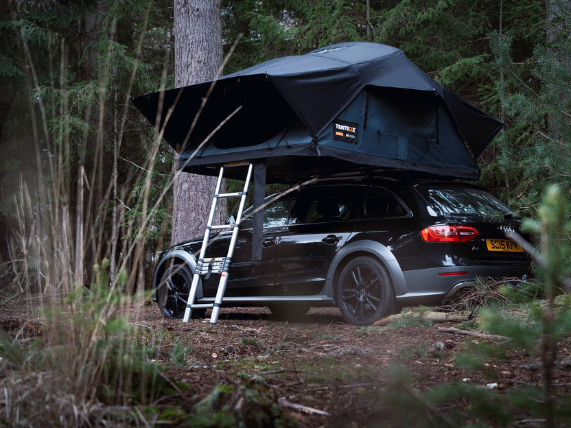 TentBox Lite XL on a black estate car in a wooded campsite